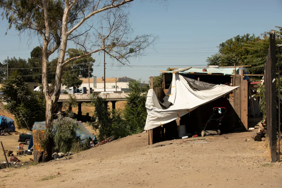 Makeshift shelter built by unhoused people on hillside overlooking freeway in Stockton, California.